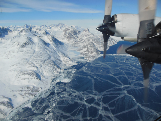 The plane flies over sea ice. The P-3B propeller can be seen out the window of the plane. Credit: Christy Hansen