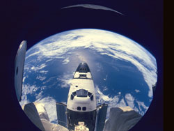 The Space Shuttle Atlantis is back-dropped against Earth.