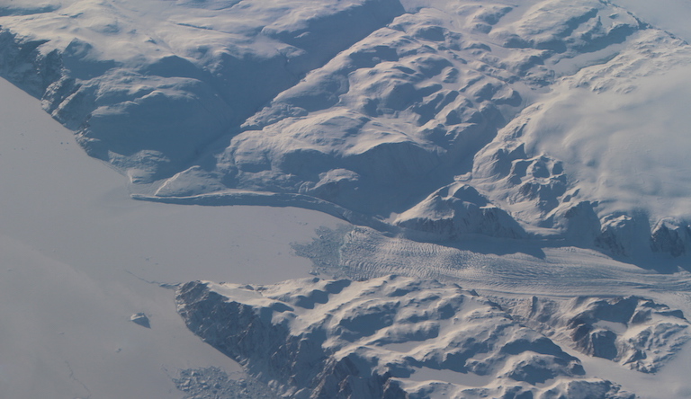 A glacier flows toward a frozen fjord on the Greenland coast, as seen from NASA's modified G-III aircraft. Credit: NASA/JPL