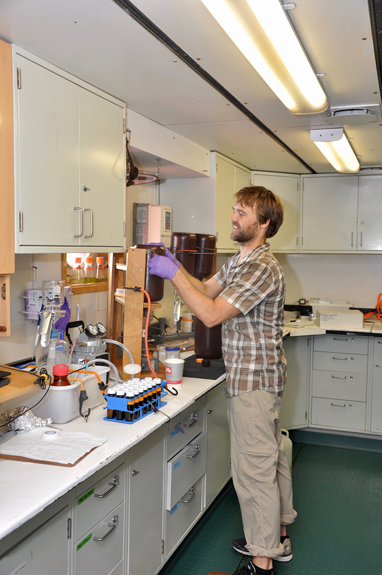 Mike Novack of NASA studies the optical and biological characteristics of sea water samples in the ship’s laboratory.