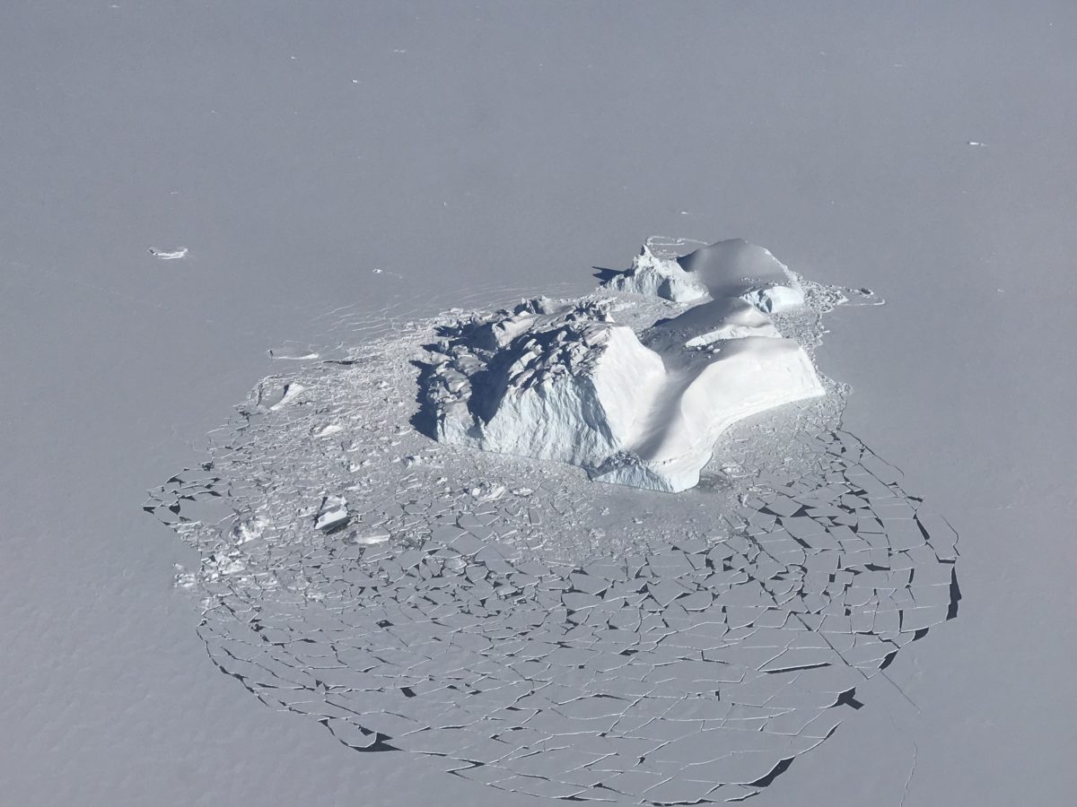 Photo of an iceberg surrounded by sea ice off the coast of Greenland.