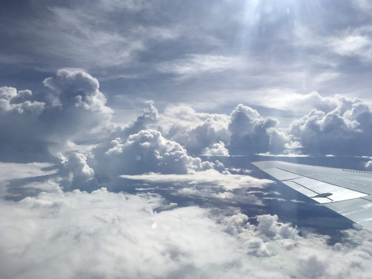 A view of the Pacific Ocean from the clouds, with a DC-8 airplane wing poking into view from the right side.