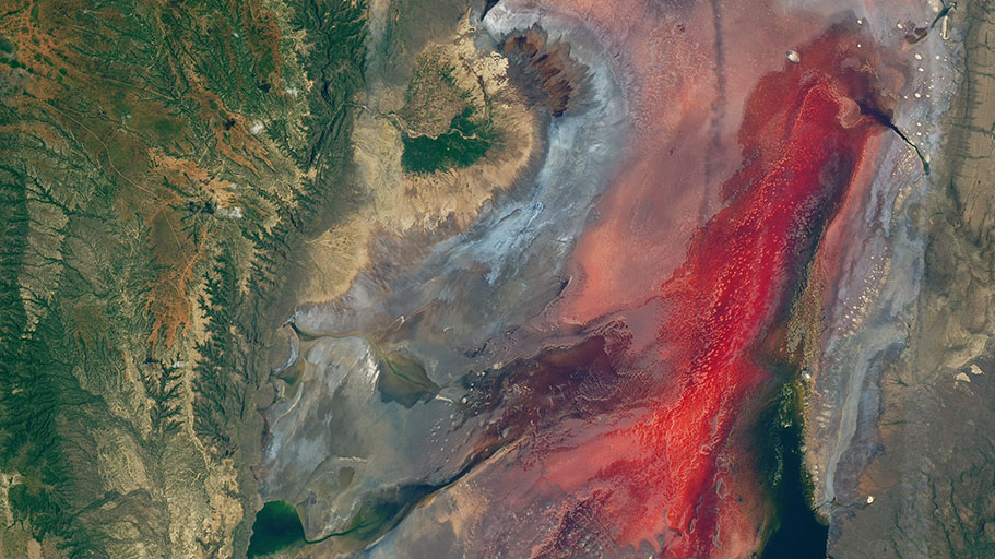 Brown, rocky land masses surround a red pool of water.