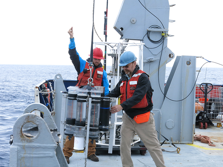 WHOI marine chemist Ken Buesseler (right) helps deploy a sediment trap from the research vessel Roger Revelle as part of the EXPORTS program.