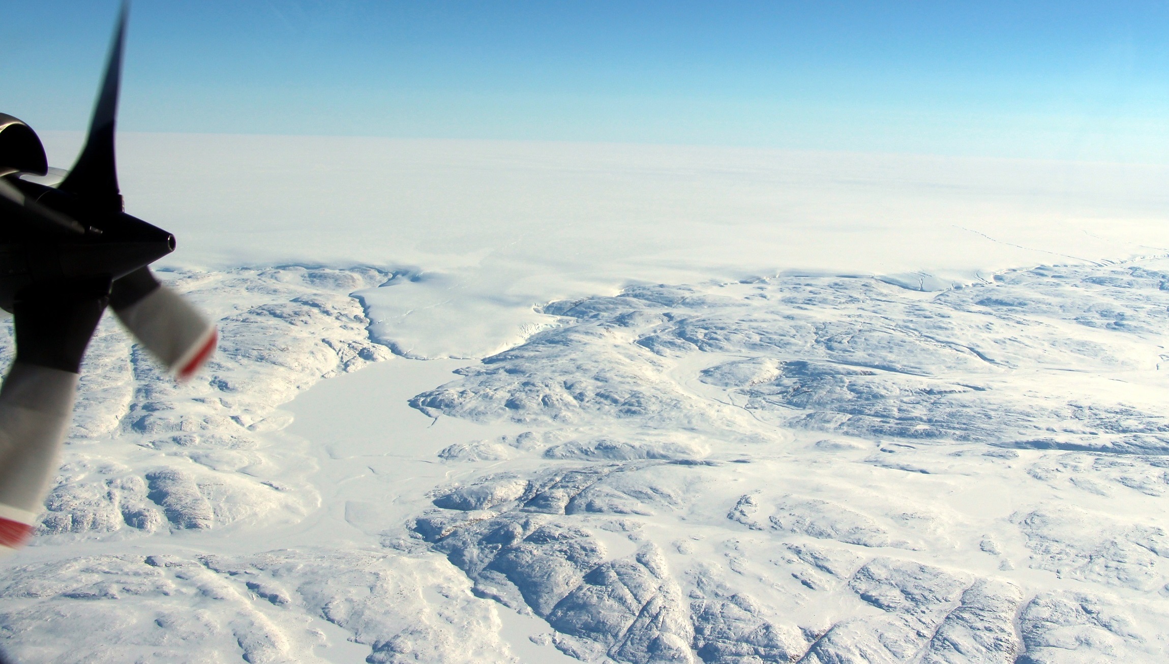 The Hiawatha impact crater is covered by the Greenland Ice Sheet, which flows just beyond the crater rim, forming a semi-circular edge.