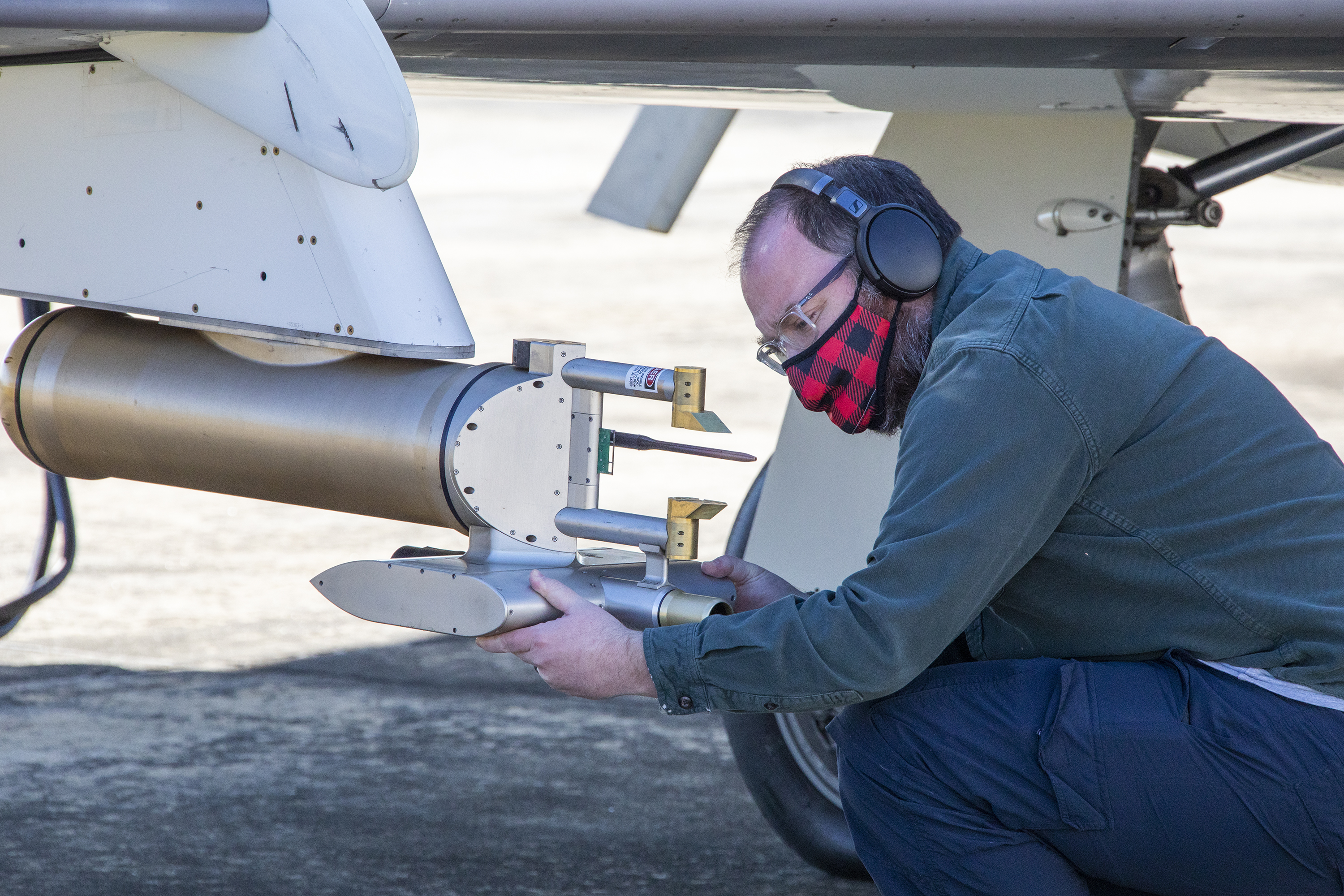 A researcher checks an instrument on an airplane prior to a flight.