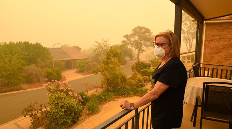 A woman on a balcony wears a face mask to protect herself against very dangerous levels of air pollution created by nearby wildfires.