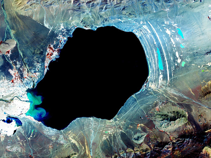 TIBETAN DEPTHS: Dagze Co (Lake) is one of many inland lakes in Tibet. In glacial times, the region was considerably wetter, and lakes were correspondingly much larger. This is evident by the numerous fossil shorelines that circle the lake, and attest to the presence of a larger, deeper lake. Changes in climate have resulted in greater aridity of the Tibetan Plateau, and drying up of the lakes. Image taken by the Advanced Spaceborne Thermal Emission and Reflection Radiometer (ASTER) on October 8, 2001.