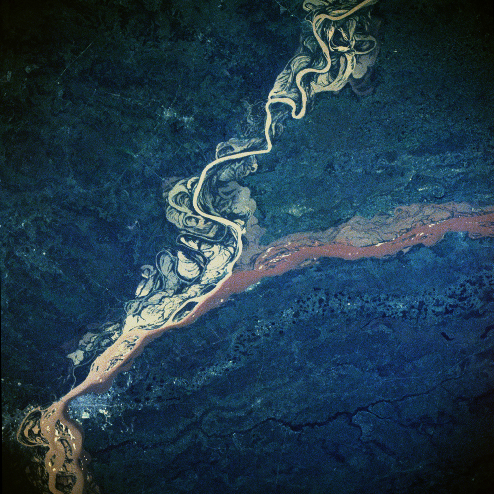 This image, taken in February 1984, shows the confluence of the Parana and Paraguay Rivers northeast of the town of Corrientes, in Argentina. The Parana is South America's second largest river (the Amazon being the largest), and the river and its tributaries are important transportation routes for landlocked cities in Argentina, Paraguay, Bolivia and Brazil. Both the Parana and Paraguay Rivers are loaded with sediment; the Paraguay (left) contains a tan sediment and the Parana (right) contains a reddish-brown muddy sediment. As the two rivers merge in the center of the photo and begin to flow southwest, we see how their sediments remain fairly unmixed for many miles downstream.