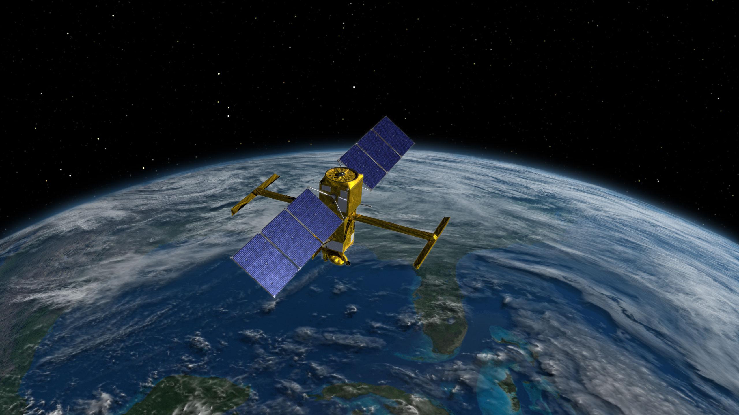 A satellite over Earth with space as a background. The satellite is maily gold colored with two box structures. From the top gold box there are three rectangular blue solar panels that extend from each side. From the middle there are two gold colored t-shaped structures that extend out in the opposite direction from the solar panels. Together they make an x letter shape.