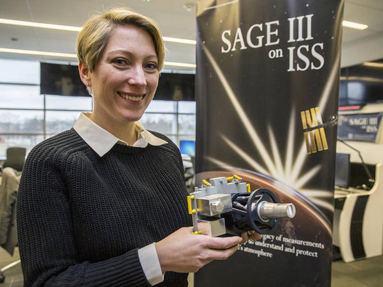Brooke Thornton, of NASA’s Langley Research Center in Hampton, Virginia, is the mission operations manager for SAGE III on the International Space Station. She is holding a scaled model of the instrument. Credit: NASA/David C. Bowman.