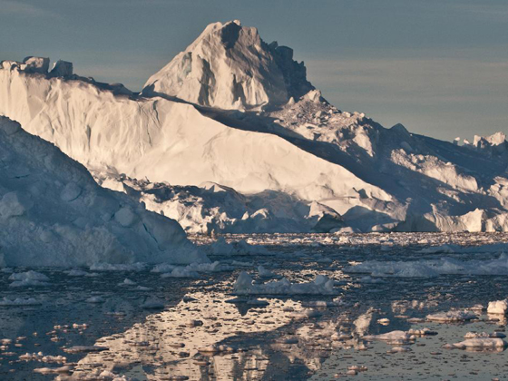 The midnight sun casts a golden glow on an iceberg and its reflection in Disko Bay, Greenland. Much of Greenland's annual ice mass loss occurs through calving of icebergs such as this. Image credit: Ian Joughin, University of Washington