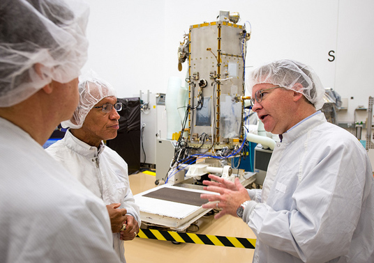 NASA Administrator Charles Bolden, left, listens as CEO and President of Orbital Sciences Corporation David Thompson, right, talks about the Orbiting Carbon Observatory 2 (OCO-2) satellite, background, in a clean room at Orbital's facility in Gilbert, AZ, on August 9, 2013. Credit: NASA/Bill Ingalls.